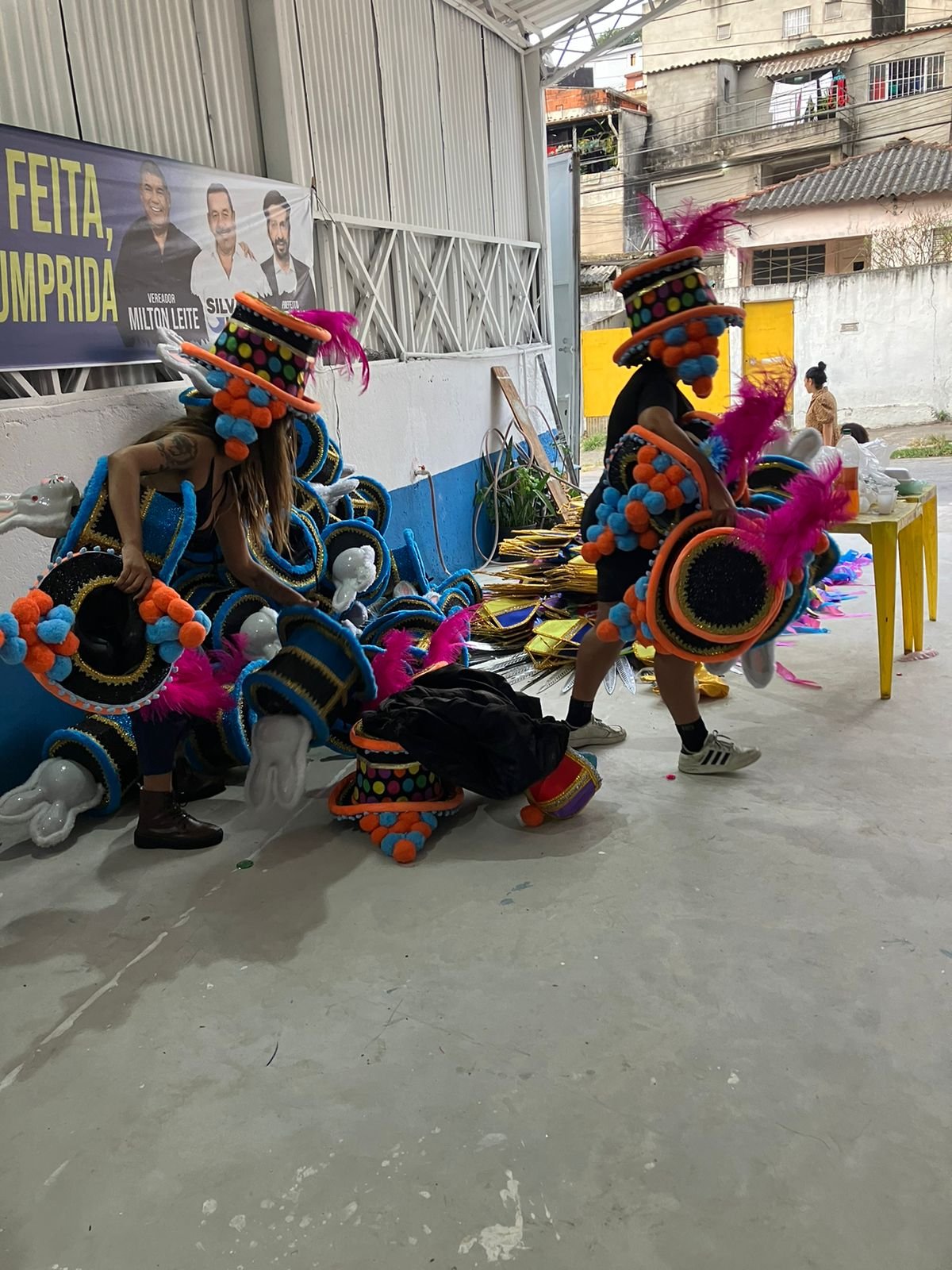 Imagem de 2 pessoas carregando fantasias de carnaval